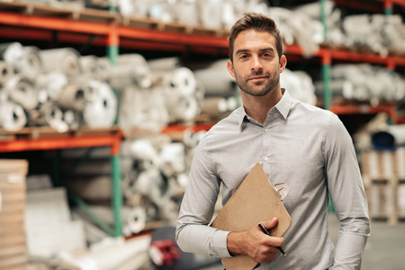 Manager standing with an inventory clipboard on a warehouse floorの写真素材