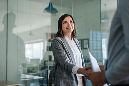 Businesswoman shaking hands with a new employee in an officeの写真素材
