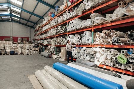 Manager checking stock on shelves in a large warehouseの写真素材