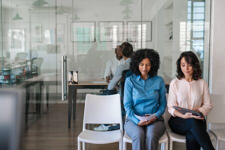 Job applicants sitting in an office waiting to be interviewed