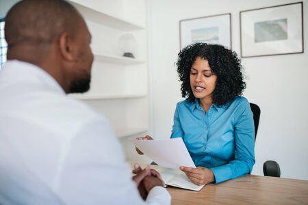 Manager reading a resume during an interview in her officeの写真素材