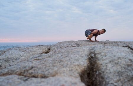 Fit man doing the eight angle pose by the oceanの写真素材