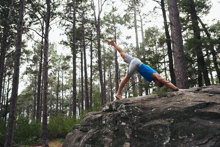 Man doing a downward facing dog pose in the woodsの写真素材