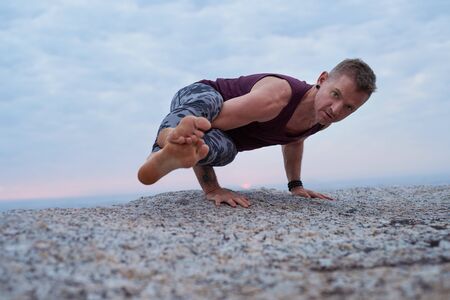 Fit man doing the eight angle pose on a rockの写真素材
