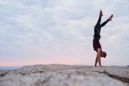 Man doing a hand stand while practicing yoga at duskの写真素材