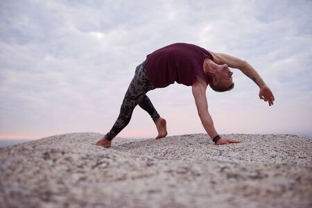 Man doing the wild thing pose on rocks at duskの写真素材