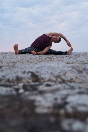 Man doing the revolved head to knee pose outsideの写真素材