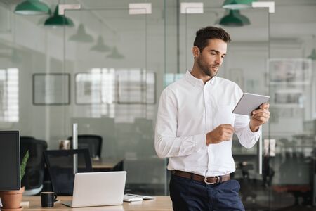 Young businessman standing in an office using a digital tabletの写真素材