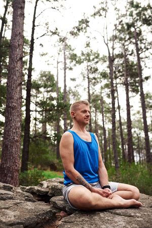 Man sitting on a rock and meditating in the forestの写真素材