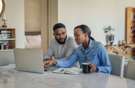 Young African American couple sitting at home doing online bankingの写真素材