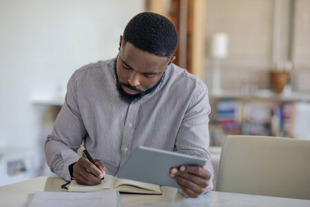 Young African American man using a digital tablet at homeの写真素材