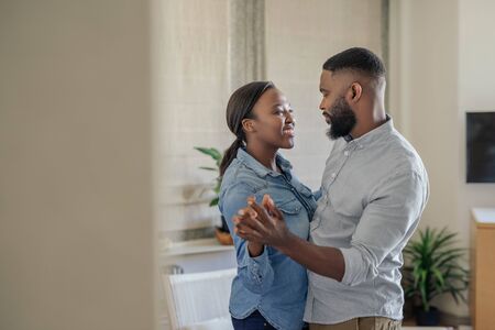 Smiling young African American couple dancing together at homeの写真素材