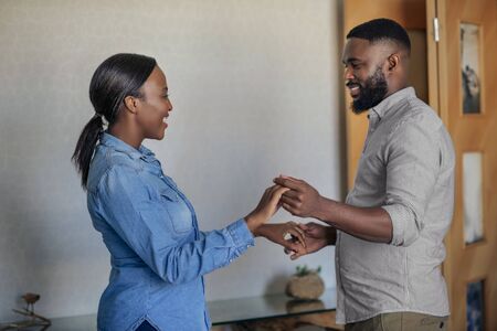 Smiling young African American couple dancing in their living roomの写真素材