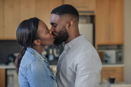 Loving young African American couple kissing at homeの写真素材