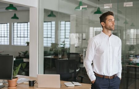 Young businessman deep in thought while standing in an officeの写真素材