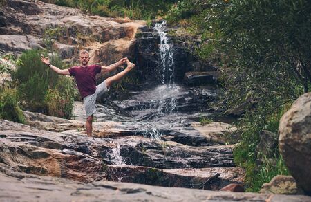 Man doing the extended standing hand to toe pose outdoorsの写真素材