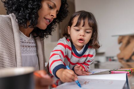 Caring mother and her adorable little girl coloring at homeの写真素材