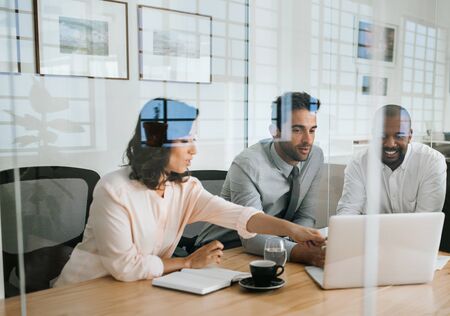 Diverse businesspeople working on a laptop inside of an officeの写真素材