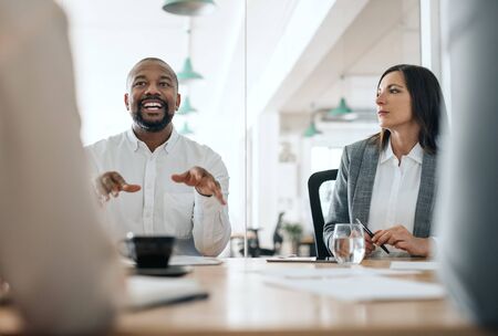 Smiling African American businessman talking with colleagues during a meetingの写真素材