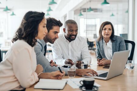 Diverse businesspeople smiling while working together on a laptop