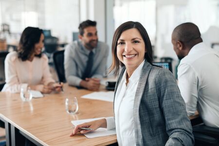Smiling businesswoman sitting with colleagues during an office meetingの写真素材