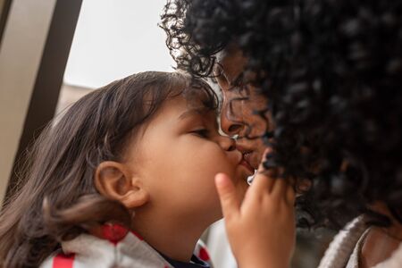Adorable little girl giving her mother a kissの写真素材