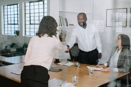 Smiling manager shaking hands with a colleague in an officeの写真素材