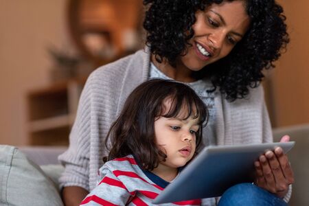 Smiling mother and adorable little daughter using a tablet togetherの写真素材