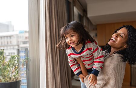 Laughing mother and small daughter playing together at homeの写真素材