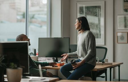 Designer talking with a male coworker during an office breakの写真素材