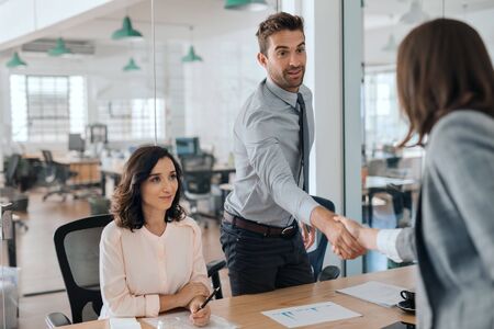 Smiling young businessman shaking hands with an office colleague