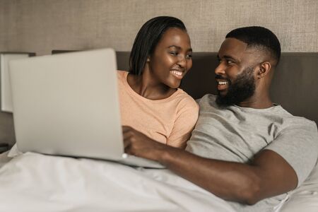 Smiling African American couple using a digital tablet in bedの写真素材