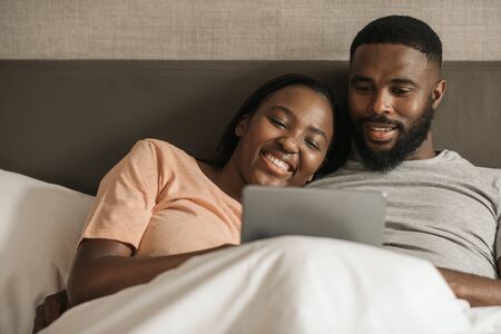 Young African American couple using a digital tablet in bedの写真素材