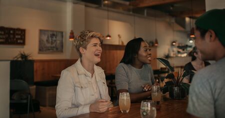 Young woman laughing with her friends in a barの写真素材
