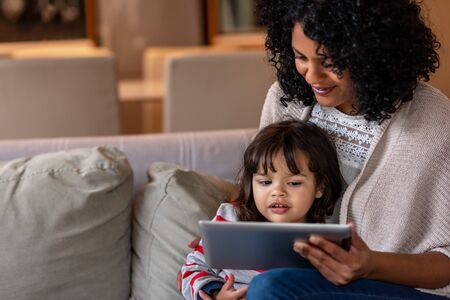 Smiling mother and little daughter using a digital tablet togetherの写真素材