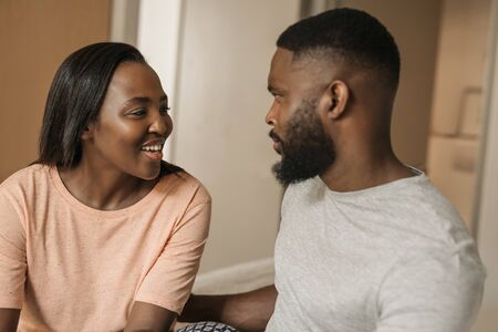 Smiling young African American couple talking together on their bedの写真素材
