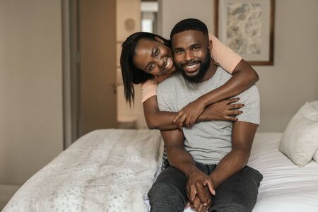 Affectionate African American couple wearing pajamas sitting on their bedの写真素材