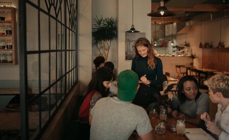 Customers ordering food from a bistro waitress in the eveningの写真素材