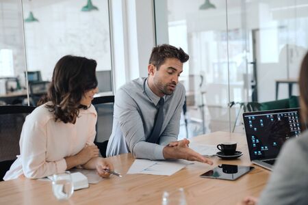 Two businesspeople discussing work with office colleagues during a meetingの写真素材