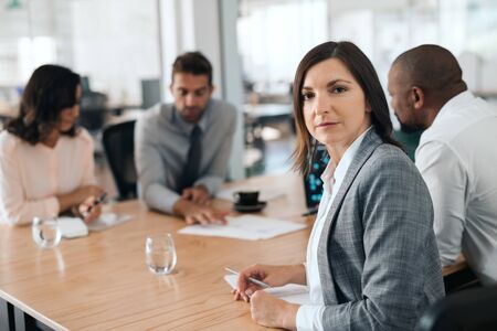 Focused businesswoman sitting with coworkers during an office meetingの写真素材