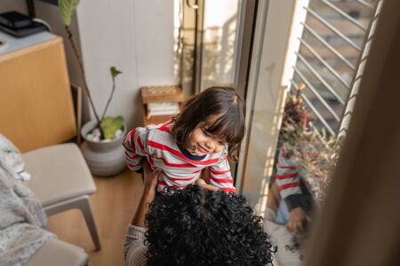Adorable little girl playing with her mother at homeの写真素材