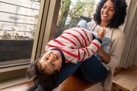 Smiling mother and cute daughter playing together at homeの写真素材