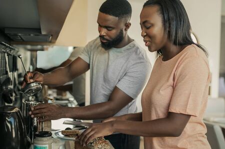 Smiling young African American couple making breakfast togetherの写真素材