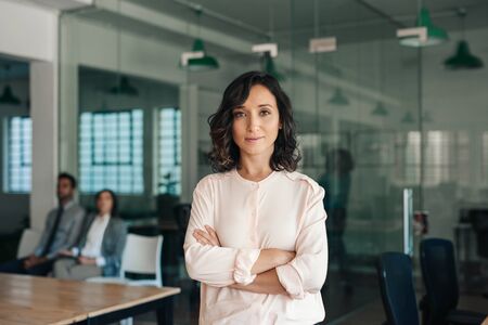 Young businesswoman standing confidently in a large modern office