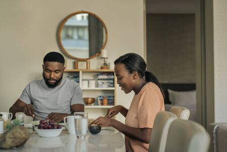 Smiling young African American couple talking over breakfast