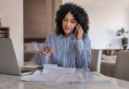 Female entrepreneur talking on her cellphone while working at homeの写真素材