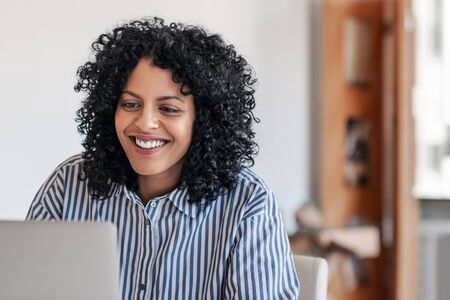 Laughing young female entrepreneur working at home on a laptopの写真素材