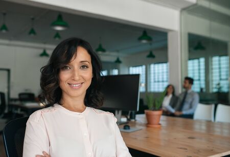 Smiling young businesswoman sitting by a table in an officeの写真素材