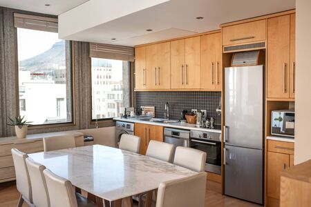 Interior of the kitchen of a small apartment with dining table, chairs and various appliancesの写真素材