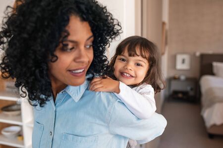 Cute little girl getting a piggyback from her smiling mom